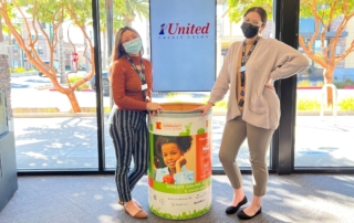 1st United staff standing with ACCFB Food Drive barrel