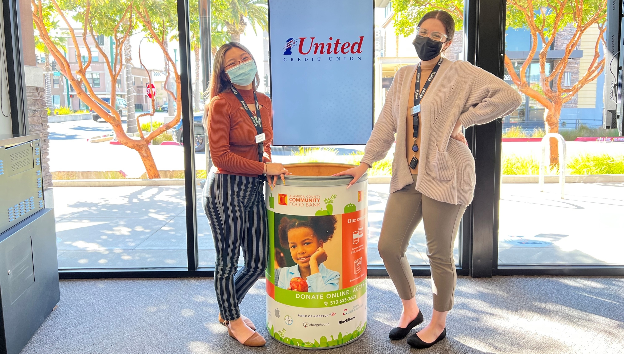 1st United staff standing with ACCFB Food Drive barrel