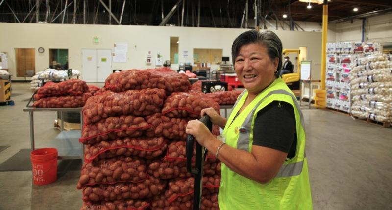 Lead volunteer Sony Yip uses a jack to move heavy sacks of potatoes to the area where volunteers will sort and bag them.