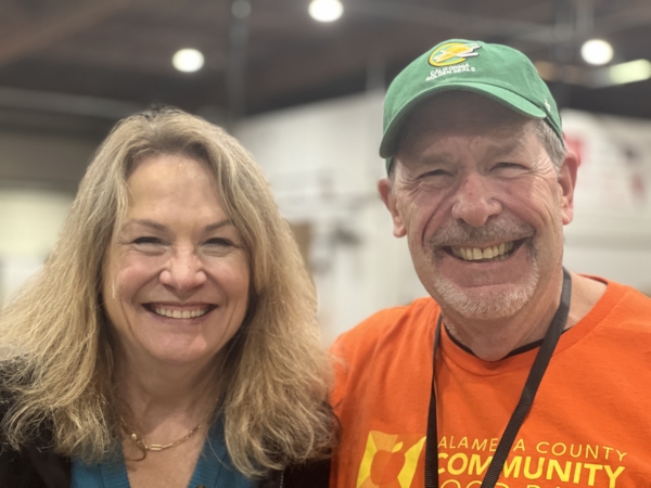 Volunteers Jennifer and Steve who have been volunteering together at ACCFB since 2018, grinning widely in the Community Engagement Center