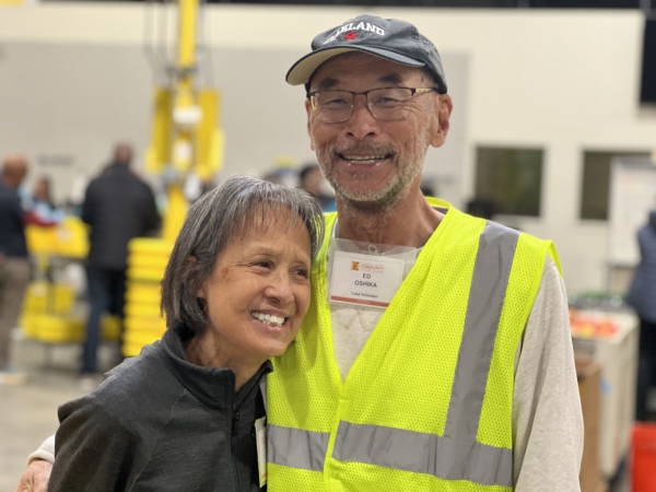 Volunteers Marcia and Ed, who have been volunteering together since 2020, standing together with wide smiles in the Community Engagement Center