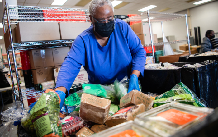 A volunteer in a blue shirt sorts a pile of packaged food